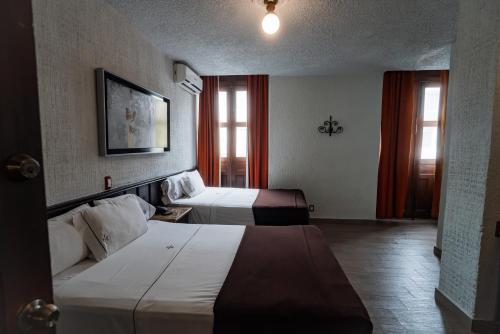 瓜达拉哈拉Hotel Don Quijote Plaza - Guadalajara Centro Historico的酒店客房带两张床和两个窗户