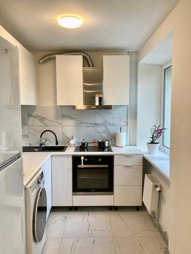 利耶帕亚Grīzupes apart的厨房配有白色橱柜和洗碗机。
