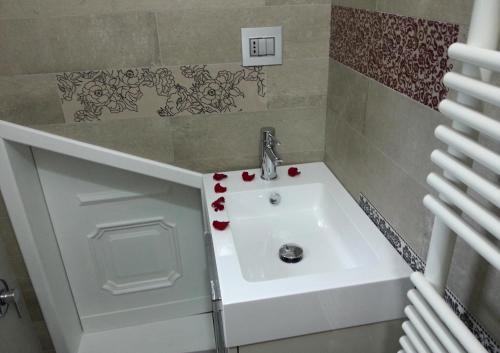 都灵曼萨达帕拉提公寓的浴室设有白色水槽,上面有红色的鲜花