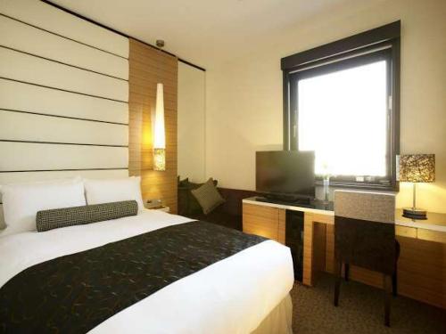 大阪大阪阿倍野特拉斯蒂酒店的一间卧室配有一张床、一张书桌和一个窗户。