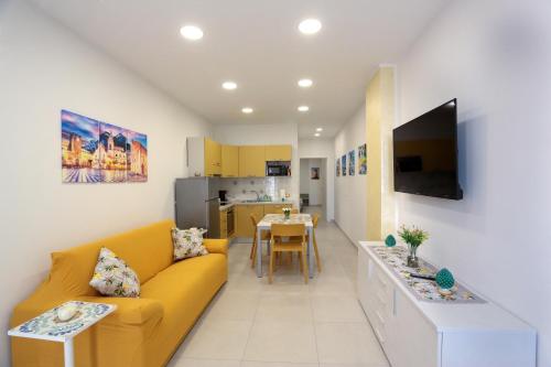 贾迪尼-纳克索斯Kris Luxury Apartments的一间带黄色沙发的客厅和一间厨房