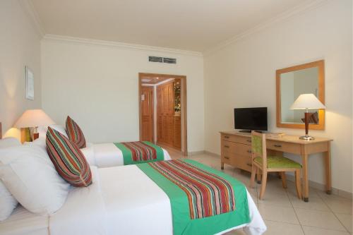 塔巴Movenpick Taba Resort & Spa的酒店客房设有两张床、一张桌子和一面镜子