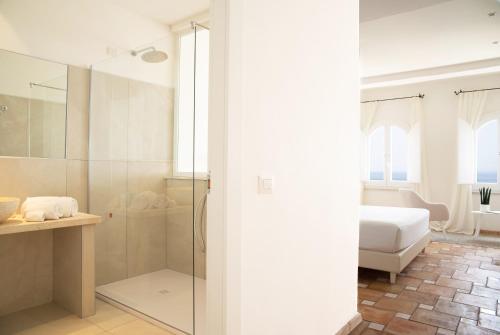 斯库索港Relais La Ghinghetta的一间带玻璃淋浴的浴室和一张床
