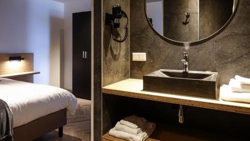 斯泰伦丹Dock Hotel Stellendam的一间带水槽、床和镜子的浴室