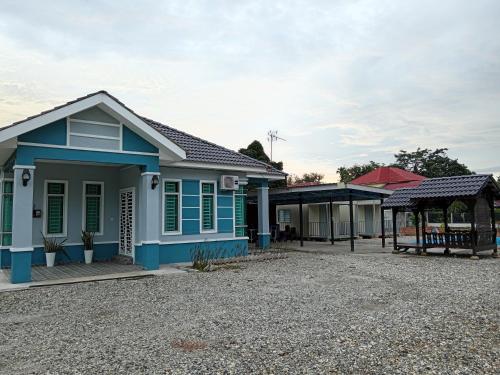 双溪大年Homestay Pinang Tunggal的砂石车道上一所蓝色绿色装饰的房子
