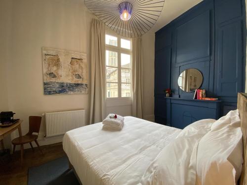 里摩日Les Chambres du Cloître的卧室拥有蓝色的墙壁和白色的床。