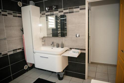 圣皮埃尔La case à Nath - Piscine chauffée et jacuzzi的浴室设有白色水槽和镜子