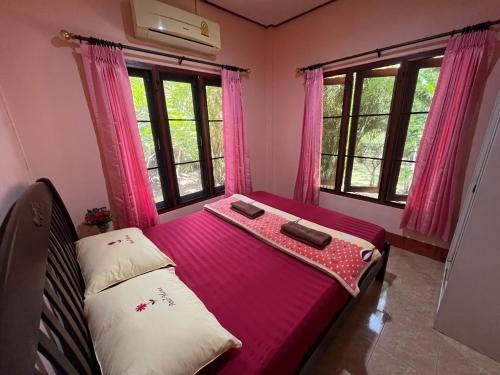 卡农快乐度假村 的客房设有带粉红色窗帘和窗户的床。