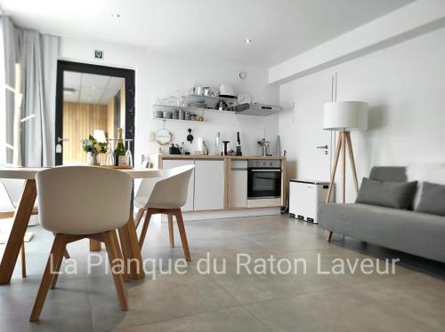 LierneuxLa planque du raton laveur的厨房以及带桌子和沙发的客厅。