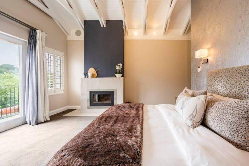 开普敦Luxe Family Home with Solar Power in Secure Hout Bay Estate的一间卧室配有一张床和一个壁炉