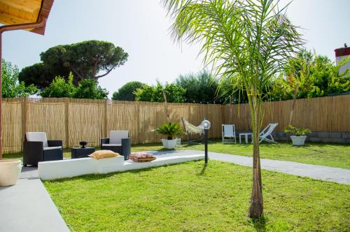 泰拉奇纳VILLA AMBROSIA 172 A的一个带棕榈树、椅子和围栏的花园