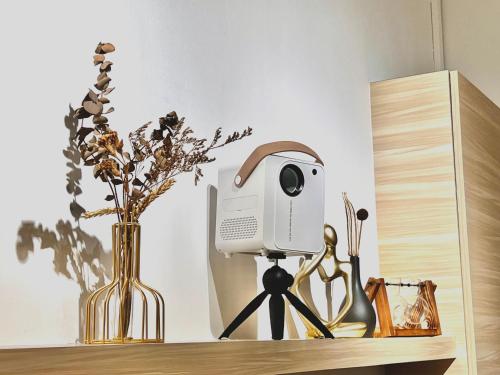 居銮HeyMuji Projector-Netflix-Darts-Near Lotus的花瓶旁的三脚架上的相机