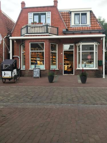 斯希蒙尼克奥赫Logeren bij de bakker的前面有车的砖街上的商店