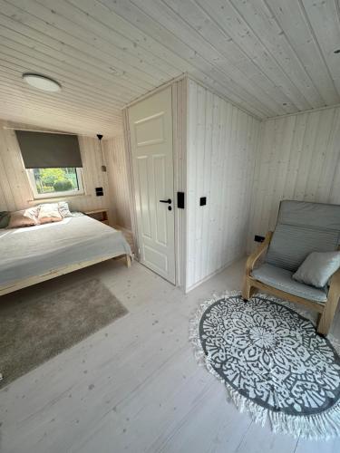 库雷萨雷Fully equipped new tiny-house的一间卧室配有一张床、一把椅子和地毯