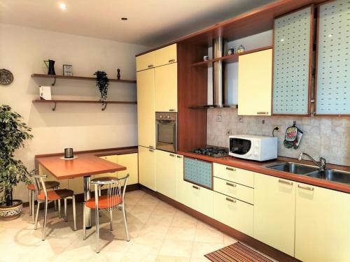 龙基德伊莱焦纳里Finestre Verdi appartamento con parcheggio的厨房配有白色橱柜、桌子和微波炉