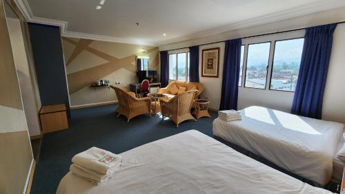 怡保园博会酒店的酒店客房带两张床和一张桌子以及椅子。