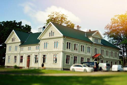 尤城Piece of Hjo Vandrarhem的一座大型白色房子,前面有汽车停放