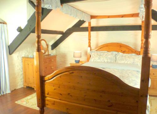 卡姆尔福德Old Newham Farm的一间卧室配有一张木床和木架