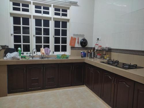 Pasir MasMegat Homestay的厨房配有棕色橱柜、水槽和窗户。