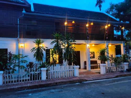 琅勃拉邦Lotus Corner - Vegan & Plant Based B&B的白色的房子,有围栏和棕榈树