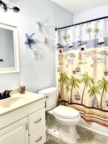 泰特斯维尔A Cozy Space Coast Retreat的浴室设有卫生间和棕榈树淋浴帘。