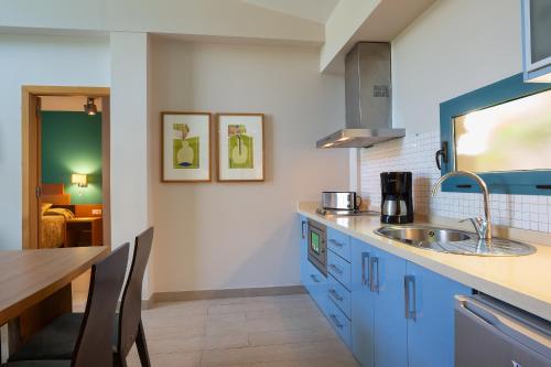莫甘海滩莫干山谷温馨公寓的厨房配有蓝色橱柜和水槽