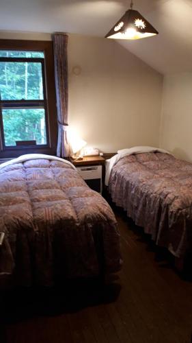 二世古比斯塔里卡纳酒店的一间卧室设有两张床和窗户。