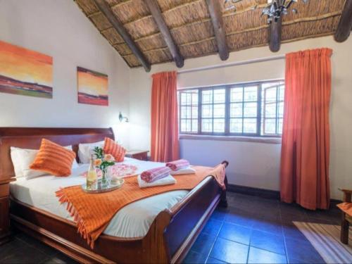 PelindabaMotozi Lodge的一间卧室配有带橙色窗帘的大床