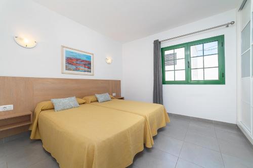 卡门港埃莱娜公寓的一间卧室配有一张带黄色床罩的床和窗户