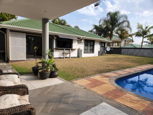 德班Umhlanga Guesthouse flat的一个带游泳池和房子的后院