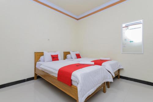 岩望RedDoorz Syariah near Alun Alun Pasuruan的一间卧室配有带白色和红色枕头的床