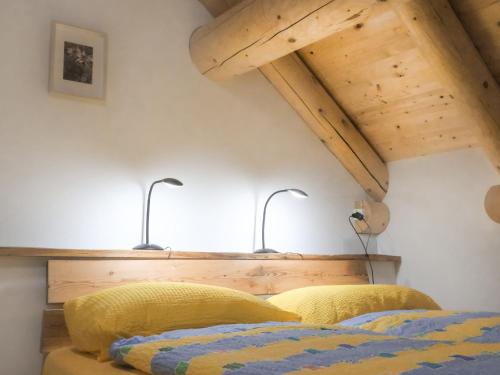MalvagliaHoliday Home Rustico La Dimora by Interhome的一间卧室设有两张床,墙上有两盏灯。