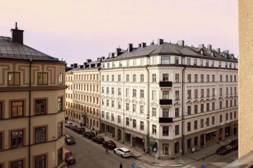 斯德哥尔摩Cosy Apartment in heart of Stockholm Sweden的一座白色的大建筑,汽车停在停车场