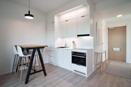 图尔库Norden Homes 2-Bedroom Apartment的厨房配有白色橱柜和木桌