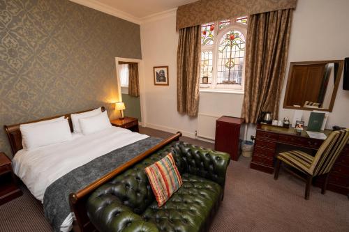 马尔堡Castle and Ball by Greene King Inns的酒店客房配有一张床和一张皮沙发