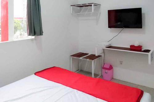 MagetanRedDoorz near Alun Alun Magetan的一间卧室配有一张带红色毯子的床和一台电视。