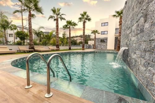 阿基欧斯尼古拉斯Lazar Lux Suites - Ammoudara的一个带瀑布和棕榈树的游泳池
