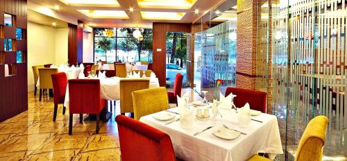 达卡West Park Inn的一间设有白色桌子和红色椅子的餐厅