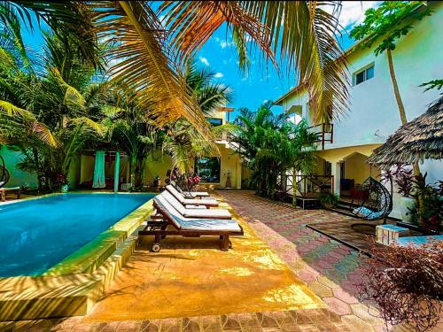 帕杰CeZeRe THE PALM HOTEL的一座房子旁的游泳池,设有躺椅和棕榈树