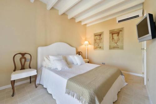 伊维萨镇Dalt Vila House的一间卧室配有一张床、一台电视和一把椅子