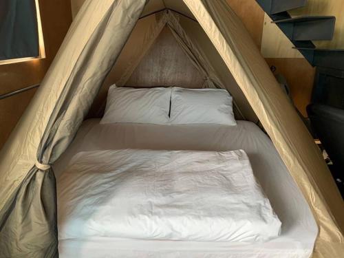 恒春古城半岛肆集的帐篷内的一张床位,配有白色床单和枕头