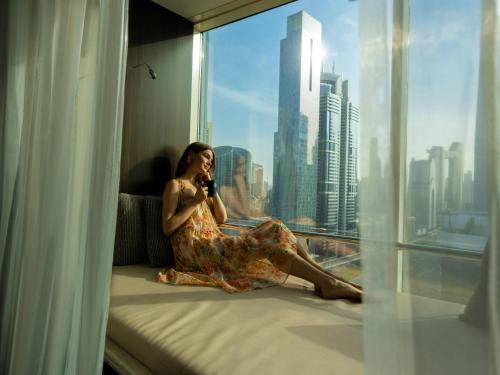迪拜迪拜罗塔纳大厦酒店的坐在窗台上的女人用手机说话