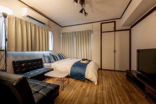 东京渋谷まで電車で1駅 2分池尻大橋駅まで徒歩8分民泊アパート的一间卧室配有一张床、一张沙发和一台电视。