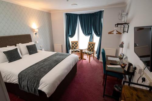 切尔滕纳姆Rising Sun Hotel by Greene King Inns的配有一张床和一张书桌的酒店客房