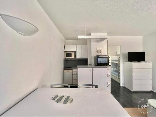 阿卡雄Studio ARCACHON的厨房配有白色橱柜和桌椅