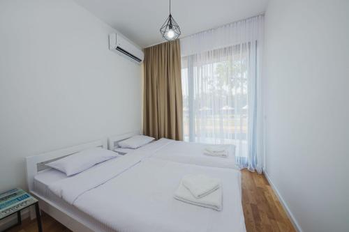 波德戈里察KOKO VILLAGE的卧室配有白色的床和窗户。