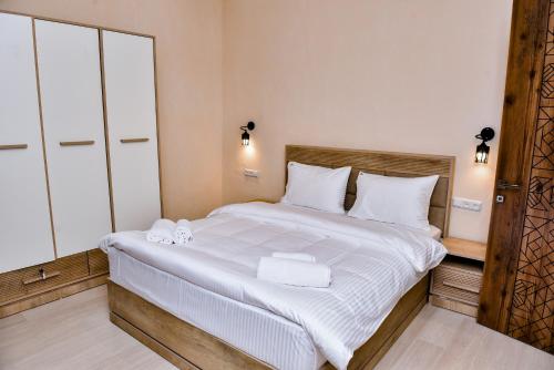 迪利然Maestro Rest House Dilijan的卧室配有一张带白色床单和毛巾的大床。