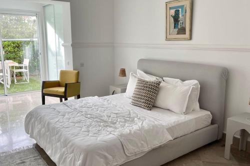 拉马萨Sindbad House的卧室配有白色床、椅子和窗户