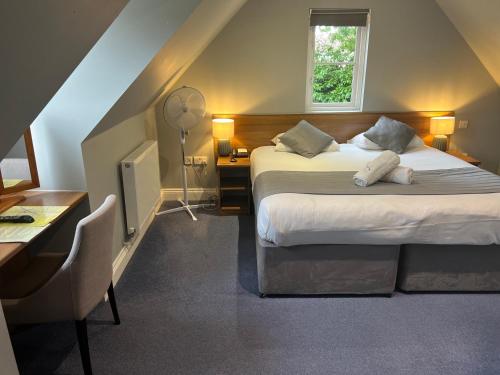 霍利Corner House Hotel Gatwick with Holiday Parking的一间卧室配有一张床和一张带风扇的书桌