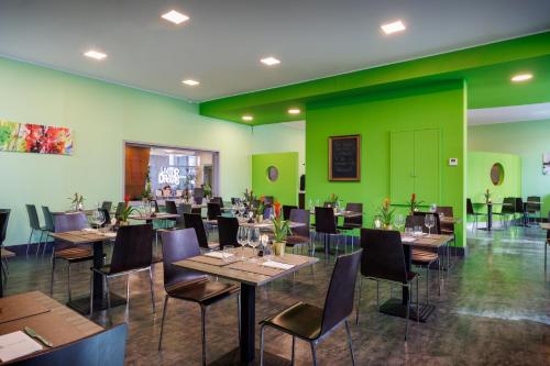 米兰iH Hotels Milano Lorenteggio的餐厅设有桌椅和绿色的墙壁